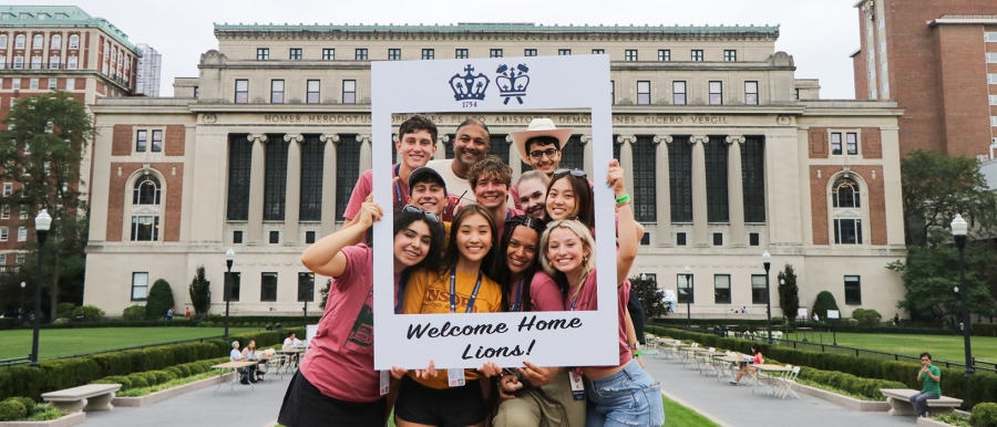 Orientation Leaders pose with a "Welcome Home, Lions" frame in front of Butler Library at move-in
